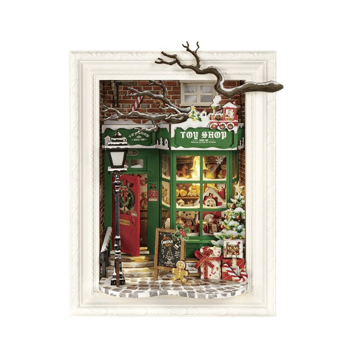 Rolife Santa’s Toy Shop DIY billedramme vist forfra med grønt legetøjsvindue, rød dør, juletræ, gaver og gade-lanterne