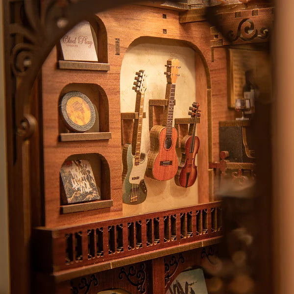 Nærbillede af CUTEBEE The Secret Rhythm DIY book nook med tre miniatureguitarer og violin montér på væg